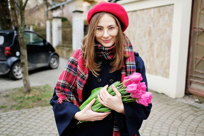 Young french millennial girl in beret and coat with tulips in hands