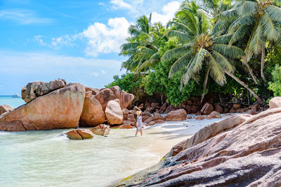 Scenic view of rock formation on beach. woman, one person, palm trees, tropical.