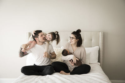 Happy millennial family plays together on bed