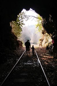 Rear view of men standing on railroad track