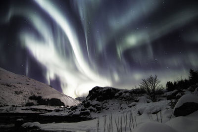 Scenic view of snowcapped mountains against sky at night