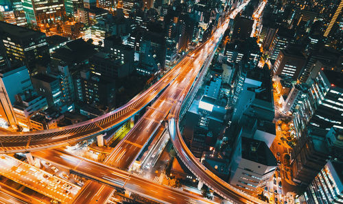 High angle view of illuminated street amidst buildings at night