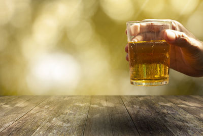 Hand holding glass of beer on table