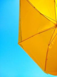 Low angle view of yellow umbrella against clear blue sky