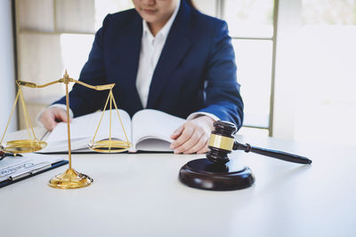 Midsection of female lawyer reading book in courthouse