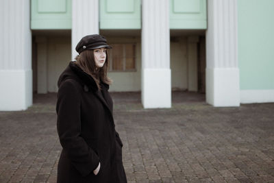 Beautiful woman wearing hat looking away while standing outdoors