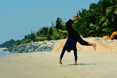 Young man doing cartwheel at beach