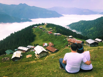 Rear view of people sitting on grassy field