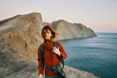 Woman standing by sea against sky