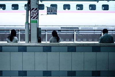 Rear view of people standing on railing