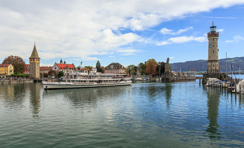 Buildings at waterfront against cloudy sky