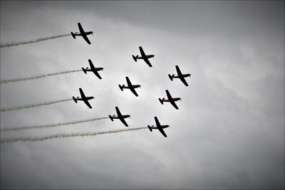 Low angle view of airshow against cloudy sky