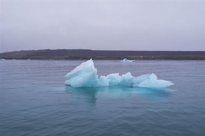 Ice floating on sea against sky