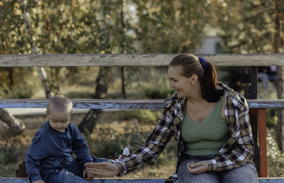A little boy on the bench with his mother