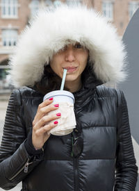 Portrait of woman in fur coat drinking coffee in city