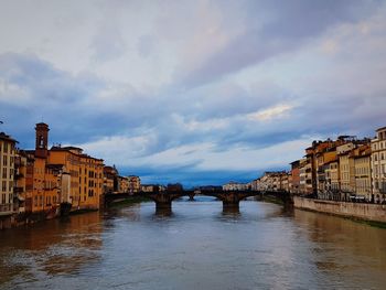 Arch bridge over river against buildings in city