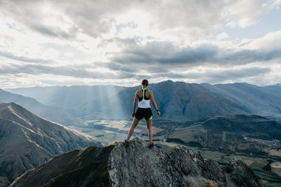 Rear view of man standing on mountain against sky