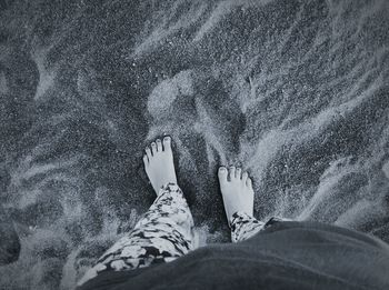 Low section of woman standing at sandy beach