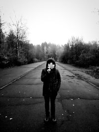 Full length portrait of young woman standing on road