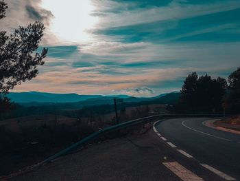 Road by mountains against sky during sunset