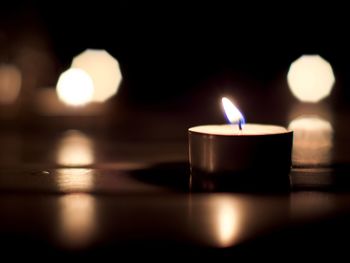 Close-up of lit tea light candles in darkroom