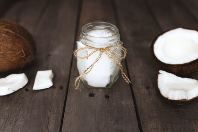 Broken coconuts on gray wooden background with jar of raw organic extra virgin coconut oil