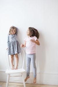 Rear view of women standing against wall at home