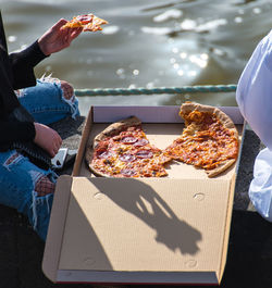Close-up of people eating pizza by water