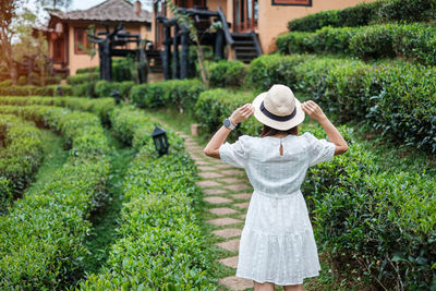 Rear view of woman standing against plants