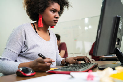 Young woman using mobile phone while sitting on table