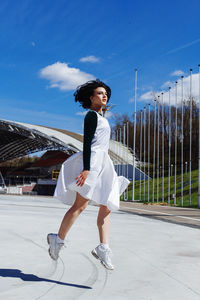 Fashionable woman jumping outdoors during sunny day