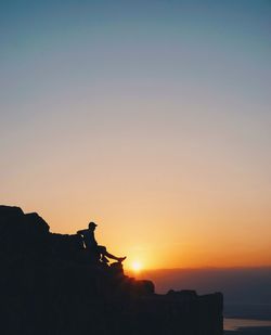 Silhouette man standing on beach against clear sky during sunset