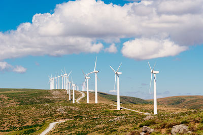 Wind turbines for power generation on hill against blue sky