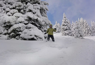 Man skiing on snow covered tree against sky