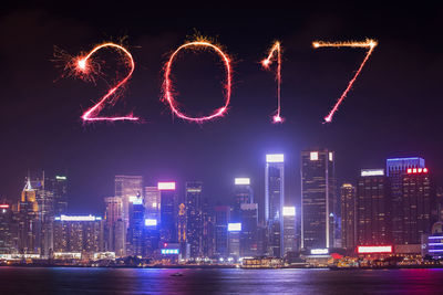 Firework display over illuminated city buildings at night