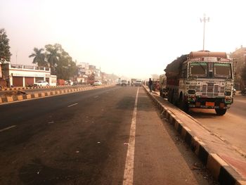 Cars on street in city against clear sky