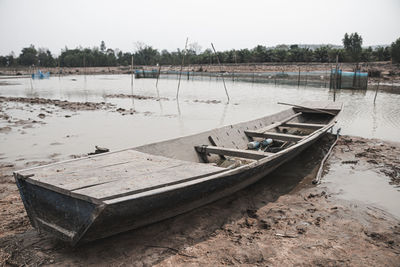 Abandoned boat moored on beach against sky