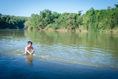 Man surfing in lake against trees