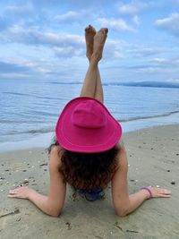 Midsection of woman with arms raised at beach against sky