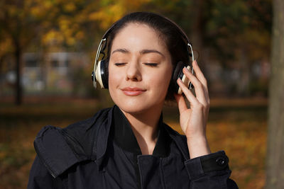 Close-up of young woman listening to music through headphones at park