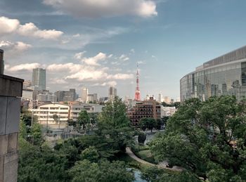 Trees and buildings in city against sky