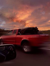 Red car against sky during sunset