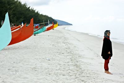 Young woman wearing hijab while standing at beach