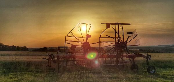 Traditional windmill on field against sky during sunset