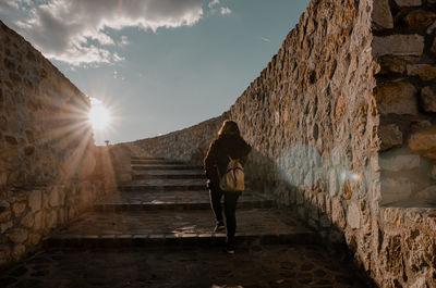 Rear view of girl walking on staircase against wall