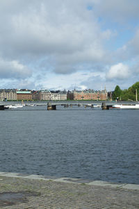 Bridge over river by buildings against sky