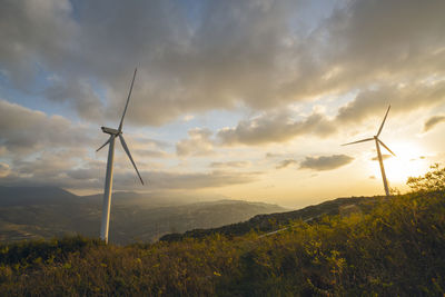 Wind turbines on field against sky