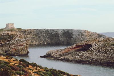 Rock formations by sea against sky