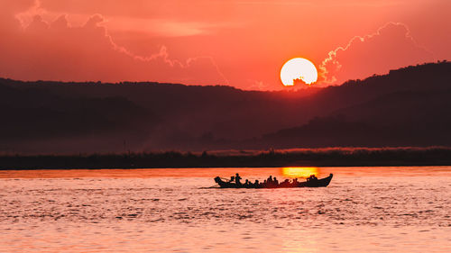 Silhouette boat in sea against orange sky