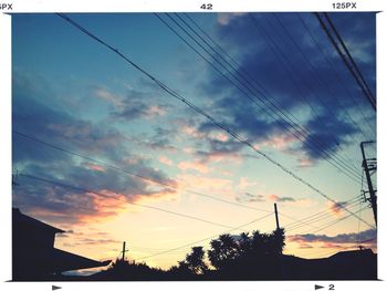 Low angle view of electricity pylon against cloudy sky